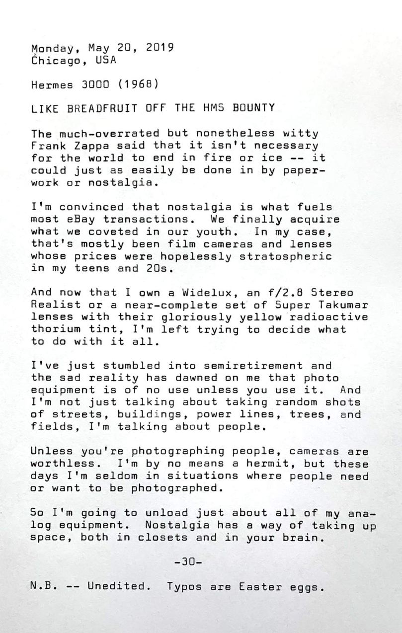 This is a photo of a typewritten page that contains the following text. Monday, May 20, 2019. Chicago, USA. Hermes 3000 (1968). Like breadfruit off the HMS Bounty. The much-overrated but nonetheless witty Frank Zappa said that it isn' t necessary for the world to end in fire or ice — it could just as easily be done in by paperwork or nostalgia. I’m convinced that nostalgia is what fuels most eBay transactions. We finally acquire what we coveted in our youth.	In my case, that's mostly been film cameras and lenses whose prices were hopelessly stratospheric in my teens and 20s. And now that I own a Widelux, an f/ 2.8 Stereo Realist or a near—complete set of Super Takumar lenses with their gloriously yellow radioactive thorium tint, I t m left trying to decide what to do with it all. I've just stumbled into semiretirement and the sad reality has dawned on me that photo equipment is of no use unless you use it. And I 'm not just talking about taking random shots of streets, buildings, power lines, trees, and fields, I 'm talking about people. Unless you' re photographing people, cameras are worthless. I’m by no means a hermit, but these days I’m seldom in situations where people need or want to be photographed. So I 'm going to unload just about all of my analog equipment.	Nostalgia has a way of taking up space, both in closets and in your brain. Note: Unedited. Typos are Easter eggs.