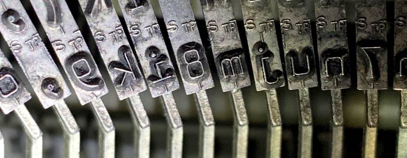 Close-up view of typewriter type slugs that show insignias of the letters S and TP.