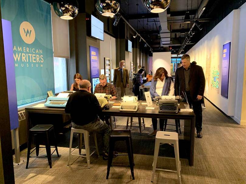 Photo of several people using some of the eight typewriters available for visitors to try out at the American Writers Museum in Chicago.