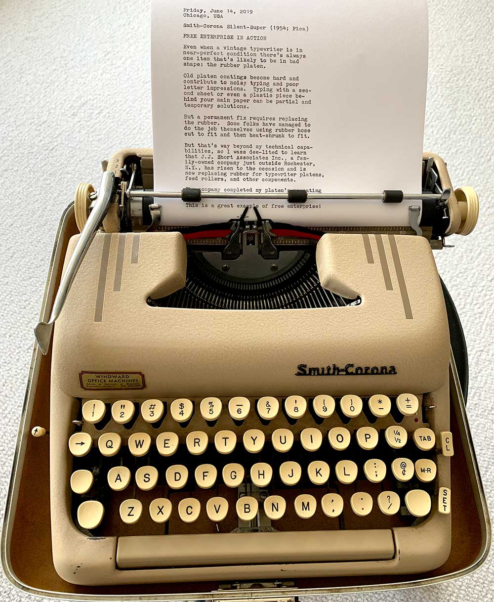 Photo of a Smith-Corona Silent-Super portable typewriter. It is painted in what the manufacturercalled desert sand and on the left front bears a decal indicating that at some point in its life the typewriter was sold or serviced by Windward Office Machines, a company on the island of Oahu, Hawaii.