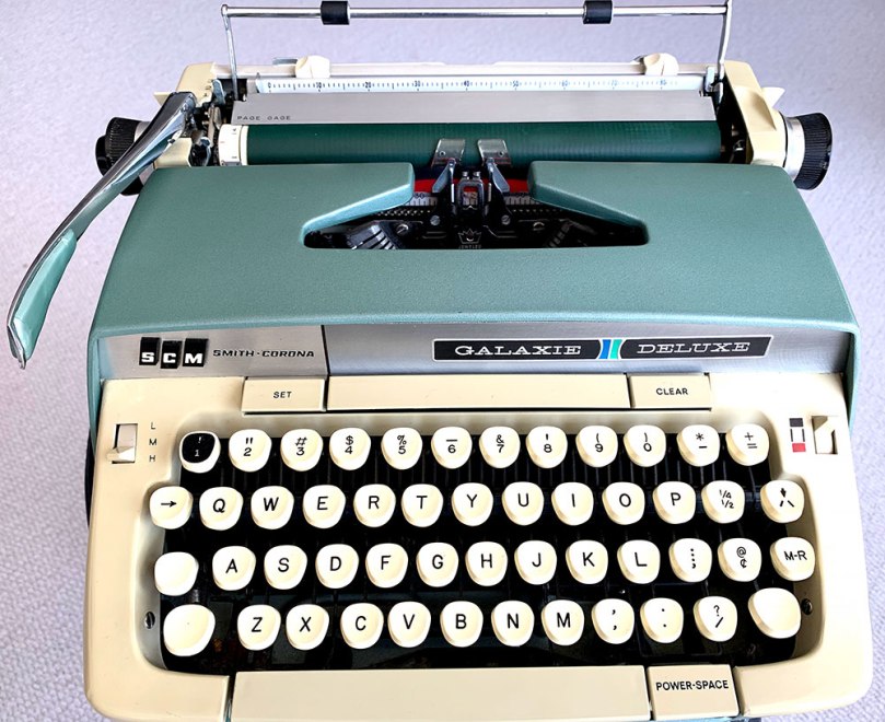 Photo of a beautiful SCM Smith-Corona Galaxie Deluxe typewriter manufactured in 1967. The machine's exterior is painted in colors associated with the era. In this case, a greenish-blue color called seafoam green complemented by creamy beige accents.